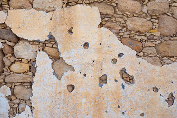 Texture of the stone. Background - a wall of solid stone. Old stucco. Stone wall. Paint drops off the wall. Background from the building. Decrepit side. Construction of the last century.