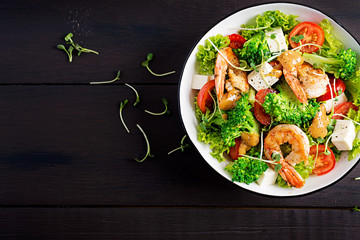 Delicious fresh salad with shrimps / prawns, broccoli, feta cheese, tomatoes, lettuce and peanut dressing. Diet menu. Top view, copy space