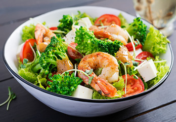 Delicious fresh salad with shrimps / prawns, broccoli, feta cheese, tomatoes, lettuce and peanut dressing. Diet menu.