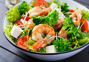 Delicious fresh salad with shrimps / prawns, broccoli, feta cheese, tomatoes, lettuce and peanut dressing. Diet menu.