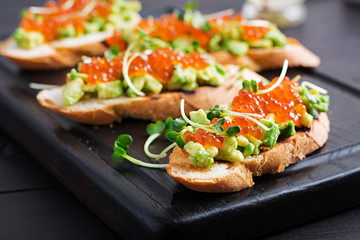Sandwiches with salmon red caviar and salsa with avocado. Sandwich for lunch. Delicious food.