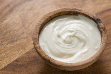 organic white yogurt in olive wood bowl on table