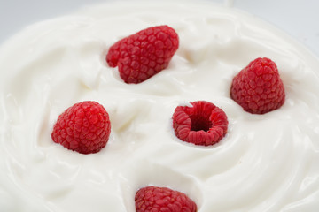 Closeup of fresh raspberries in white yogurt
