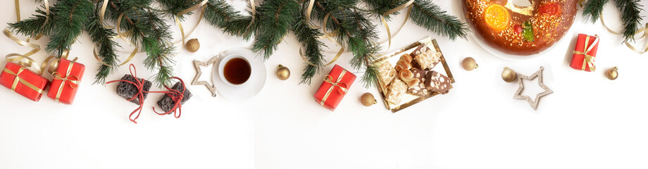 Spanish Christmas symbols for holiday concept. Roscon de reyes or Spanish holiday cake, hot chocolate, sweet coal  and turrones candies, red Christmas gifts on white background .Banner.