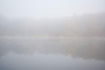 Landscape of an early morning lake and a boat with a fisherman