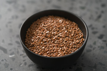 Flax seeds in black bowl on terrazzo surface with closeup