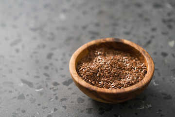 Flax seeds in olive wood bowl on terrazzo surface with copy space