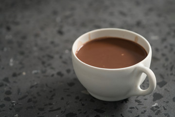 Cocoa drink in white cup on terrazzo surface with copy space