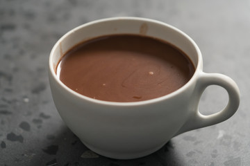 Cocoa drink in white cup on terrazzo surface closeup