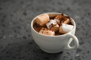 Cocoa drink with marshmallow in white cup on terrazzo surface with copy space