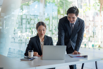 Modern business people discussing work in office and using laptop together while working.