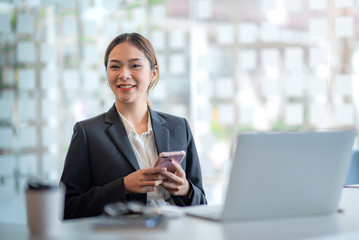 Attractive young asian businesswoman sitting using app on smartphone at office.