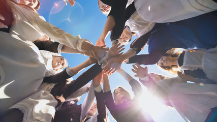 Happy friends graduates join hands together. The concept of a friendly team.
