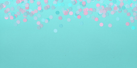 Pastel color confetti scattered on a turquoise green background.