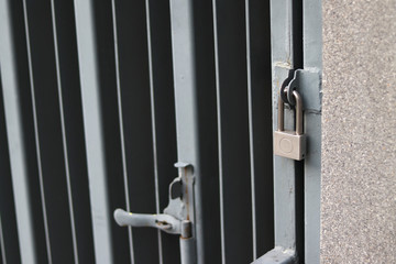 Silver padlock locking the gray iron door. Silver padlock locking steel doors safely. 