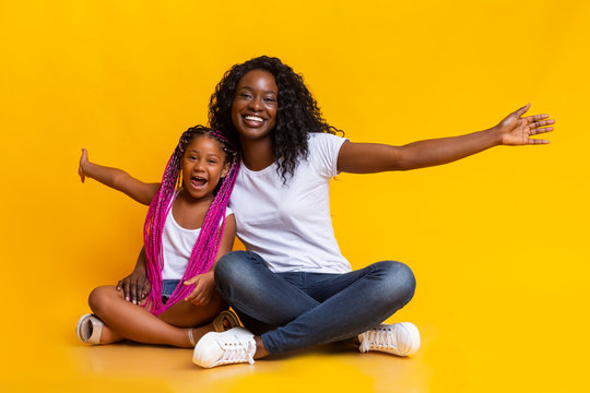 Little afro girl sitting with mom and repeating her gestures