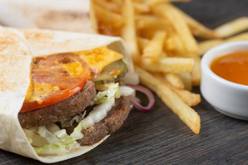 beef cutlet with pickled cucumbers, tomato, onion and cheese. french fries with sauce