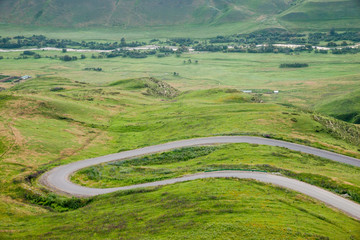 Hairpin turn of rural road in vibrant green alpine meadows