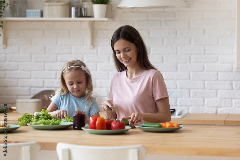 Wall mural daughter helps young mother cook healthy dinner