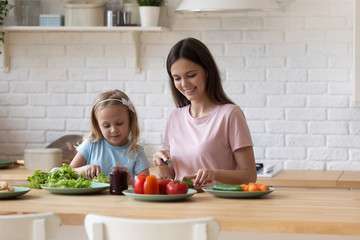 Daughter helps young mother cook healthy dinner
