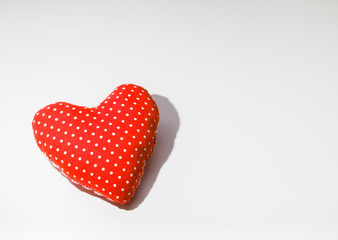 Red cloth heart on a white table.
