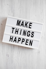 'Make things happen' words on a modern board on a white wooden background, top view. Overhead, from above, flat lay. Closeup.