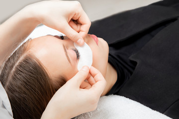 Master doctor performs procedure for beauty patches on eyes of beautiful girl skin care. Concept...