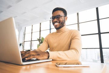 Smiling black guy at flexible office typing on keyboard