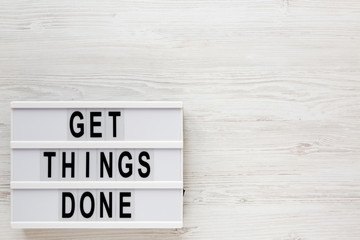 'Get things done' words on a modern board on a white wooden surface, top view. Overhead, from above, flat lay. Copy space.