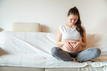 Young pregnant woman sitting on sofa