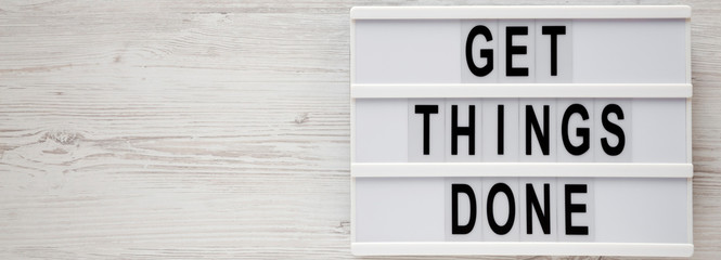 'Get things done' words on a modern board on a white wooden background, top view. Overhead, from above, flat lay. Space for text.