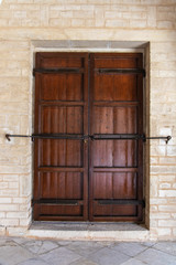 Closeup view of old brown vintage door of house closed with padlock. Vertical color photography.