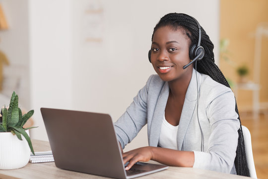 African female customer support operator wearing headset and working on laptop