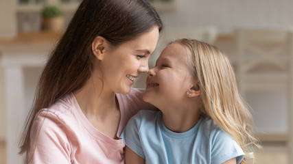 Mother and little kid daughter touching noses enjoy tender moment