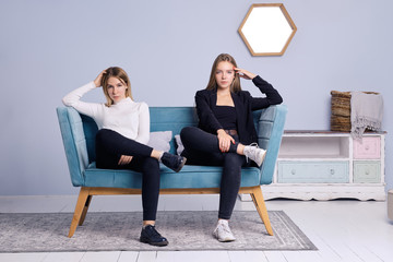 Two girls sitting together on sofa. Friendship and teenager relations.