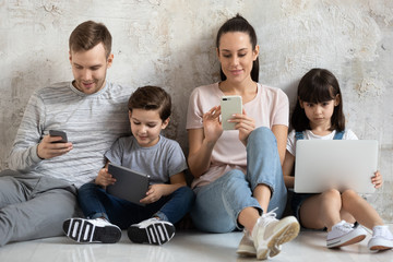 Happy family with children sit on floor using modern device.