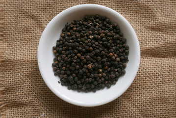 Black pepper in a white plate on rug sack. 