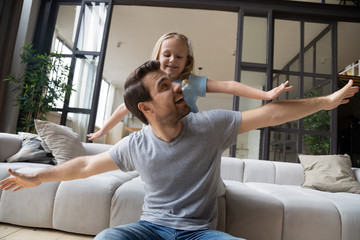 Father and daughter stretched hands play pretend like airplanes