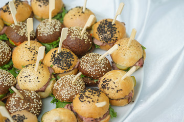 Mini burgers with meat and fish on the table prepared for the guests of the event.