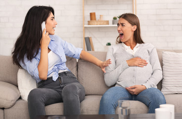 Pregnant Girl Shouting, Her Friend Calling Doctor Sitting On Couch