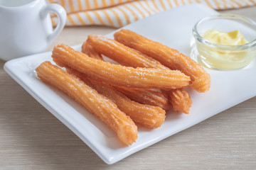Churros with sugar on plate and cheese dip