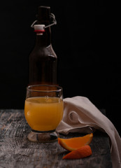 still life orange juice bottle that pours juice into a glass on a dark basis