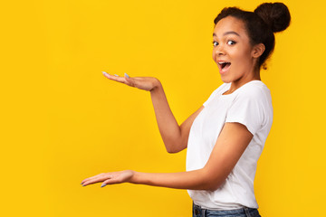 Excited black teenager pointing at free space