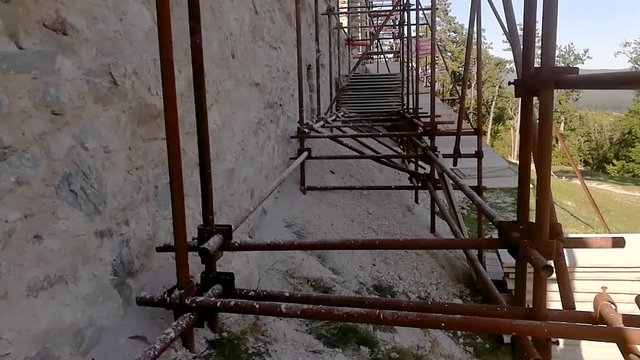 Metallic scaffolding against an old ruins wall, TILT UP