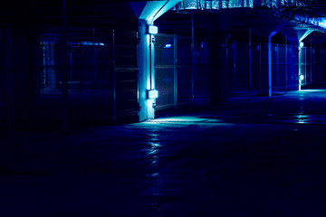 Dark empty coridor of cages with dim bulbs in underground parking garage with separate boxes....