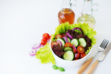 Fresh vegetable salad on white background close. Dinner of lettuce, tomatoes, onions and cucumbers. Horizontal photo with copy space.