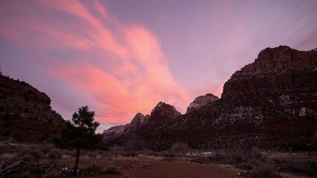 Timelapse of colorful sky in Zion as it fades away over cliffs in the desert at sunrise.