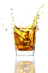 Whiskey glass with ice isolated on white background. Whisky splashes up from the glass.
