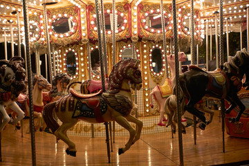 Fototapeta na wymiar Horses on a merry-go-round with lights on a Christmas night