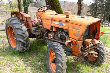 old orange tractor abandoned in a field